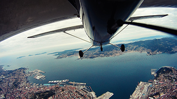 View of water and land from underneath a Cessna.