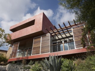 A view of the outside of a house, with movable panels partly shading the house's deck.