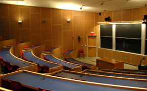 A large classroom with tiered seating and several chalkboards.