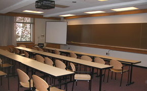 A typical classroom with rows of seats, as well as chalkboards and a projector screen at the front of the class.