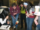 Photo of students crowded around the combined vases, still on the blowing rod.