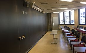 View from left side of classroom. A long table and two rows of chairs. A huge blackboard in front.