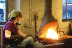 Blacksmith Amy heats metal in the forge.