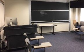 A small room with chairs around the edges and a blackboard on one wall.