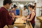 Five protective-goggle wearing students make measurements on  the frame of a wooden structure.