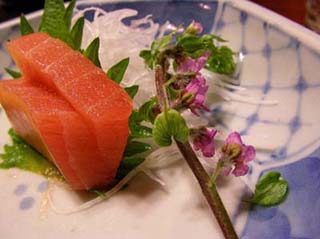 Image depicts a plate with sashimi and a flower.