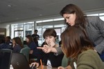 Girls sit around a laptop, and a volunteer is pointing to the computer screen.