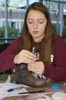 A girl is using a screwdriver to attach electronic components to a boot.