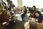 A photo of a group of girls sitting at a table, talking to a workshop volunteer.